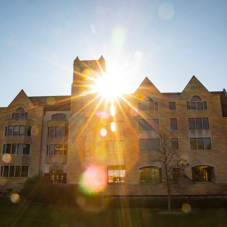 The sun rises behind O’Shaughnessy-Frey Library