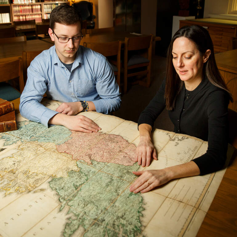 Two people examine a map from the archives