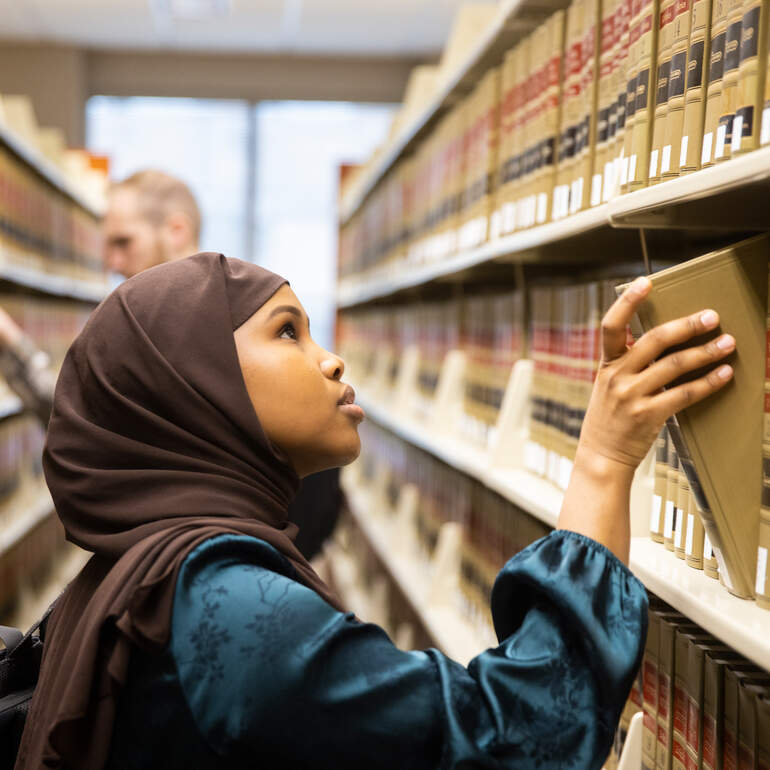 A student looks at law books on shelves