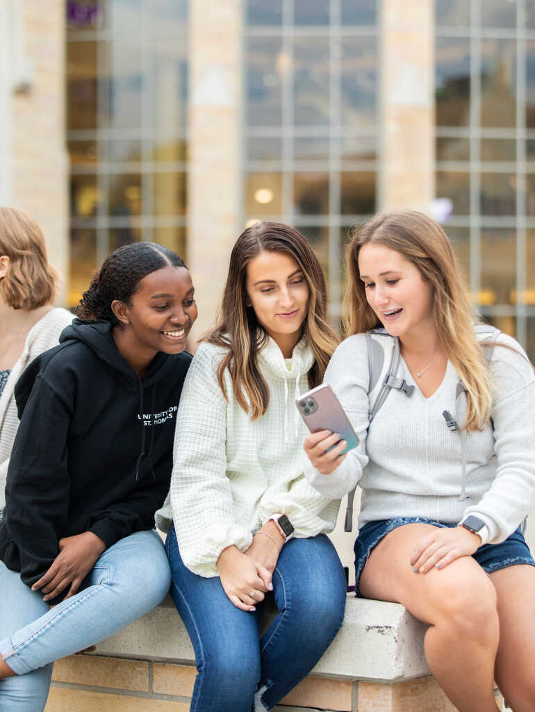Three students look at a cellphone