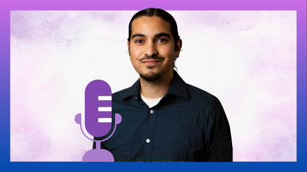 a young brown man smiles at the camera wearing a dark blue button down