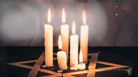 candles lit in a dark room illuminating a star of david
